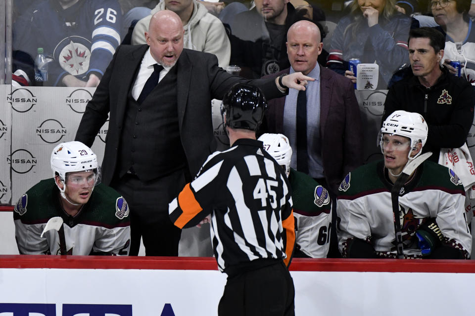Arizona Coyotes head coach Andre Tourigny, topleft, speaks with the referee, bottom center, while playing the against the Winnipeg Jets during NHL hockey game action in Winnipeg, Manitoba, Sunday, Feb. 25, 2024. (Fred Greenslade/The Canadian Press via AP)