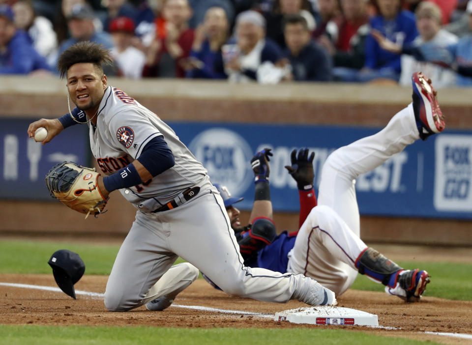 Houston Astros first baseman Yuli Gurriel (10) prepares to throw home after a collision with Texas Rangers' Nomar Mazara during the first inning of a baseball game in Arlington, Texas, Wednesday, April 3, 2019. Mazara was safe at first on the play with a single that scored Elvis Andrus. (AP Photo/Tony Gutierrez)