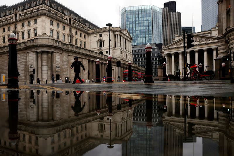 FILE PHOTO: FILE PHOTO: The Bank of England and Royal Exchange are reflected in a puddle as a pedestrian walks past in London