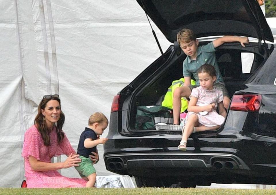 Prince George and Princess Charlotte relaxed in the back of the car with the trunk door popped open, while Kate sat with Louis on the ground.