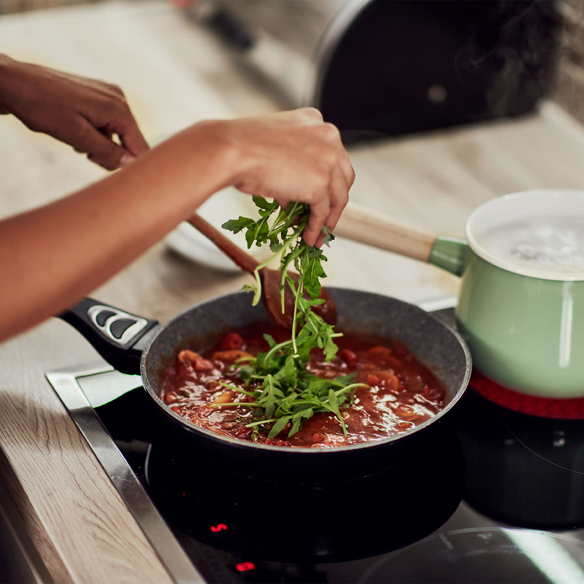 Woman cooking arugula on the stove