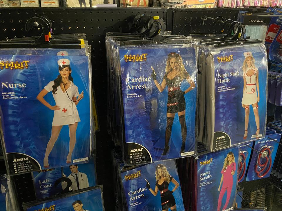 Three nurse costumes in bags hanging in a store