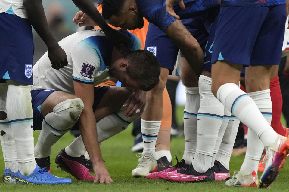 England's Harry Kane is surrounded by team mates after the World Cup quarterfinal soccer match between England and France, at the Al Bayt Stadium in Al Khor, Qatar, Sunday, Dec. 11, 2022. (AP Photo/Frank Augstein)