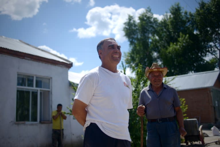 Zhang Yunshan (L), whose half-Russian father died nearly five decades ago after being imprisoned due to his background, outside his house in the village of Hongjiang in northeast China's Heilongjiang province, near the border with Russia