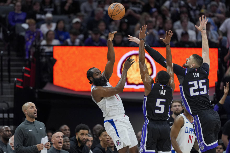 Los Angeles Clippers guard James Harden, from left, passes while defended by Sacramento Kings guard De'Aaron Fox (5) and center Alex Len (25)during the first half of an NBA basketball game Tuesday, April 2, 2024, in Sacramento, Calif. (AP Photo/Godofredo A. Vásquez)