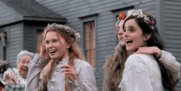 Two characters from Little Women movie, in period costume, laughing and dancing outside a house