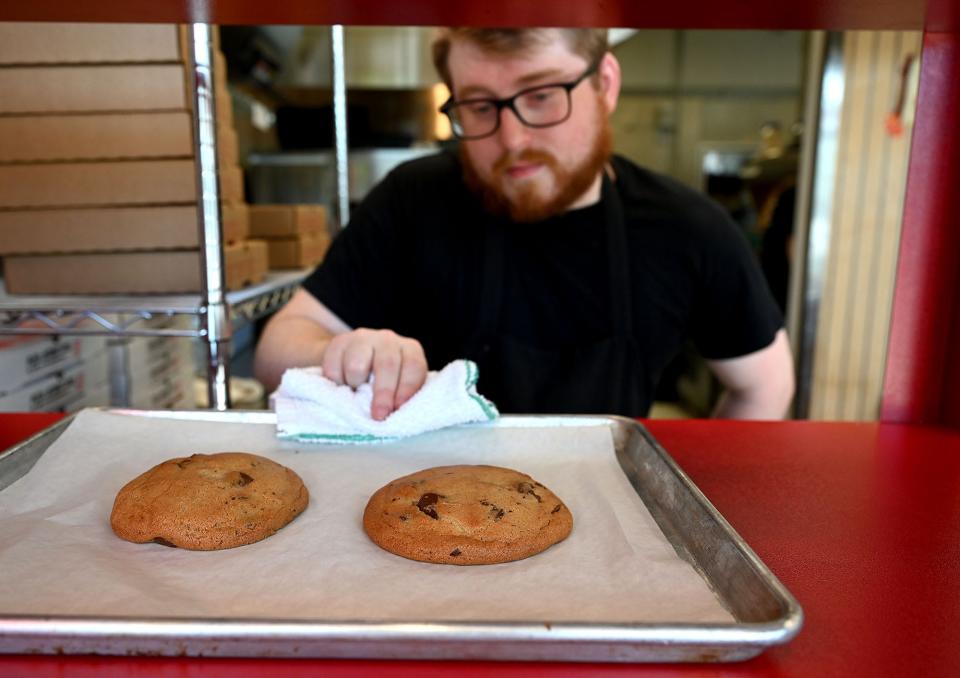 Michael Chrislu, general manager of Square Mfg. Co. Detroit style pizza in Natick, with a pair of chocolate chip cookies fresh out of the oven, May 12, 2022.