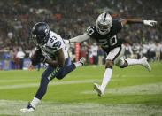 Seattle Seahawks wide receiver David Moore (83) is pushed out of the end zone by Oakland Raiders defensive back Obi Melifonwu (20) after scoring a touchdown during the first half of an NFL football game at Wembley stadium in London, Sunday, Oct. 14, 2018. (AP Photo/Tim Ireland)