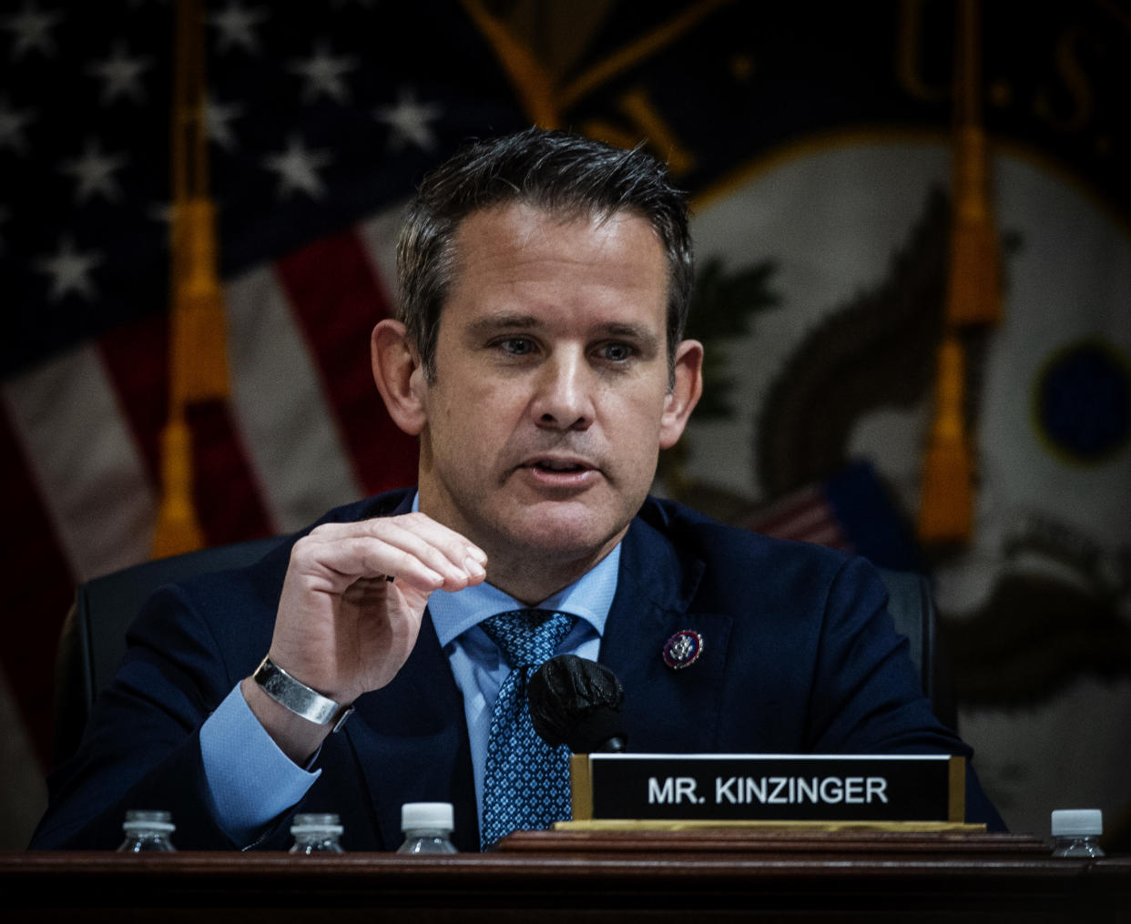 Representative Adam Kinzinger sits at a desk.