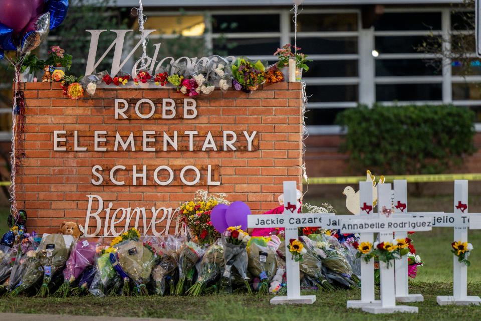 Flowers and crosses surround the sign at Robb Elementary school in a makeshift memorial to the students and teachers who were killed there in a mass shooting.