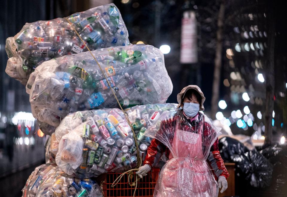 A woman wearing a face mask and a plastic bag pulls a cart loaded with bags of recyclables through the streets of Lower Manhattan during the outbreak of the novel coronavirus (which causes COVID-19) on April 16, 2020 in New York City. (Photo by Johannes EISELE / AFP) (Photo by JOHANNES EISELE/AFP via Getty Images)