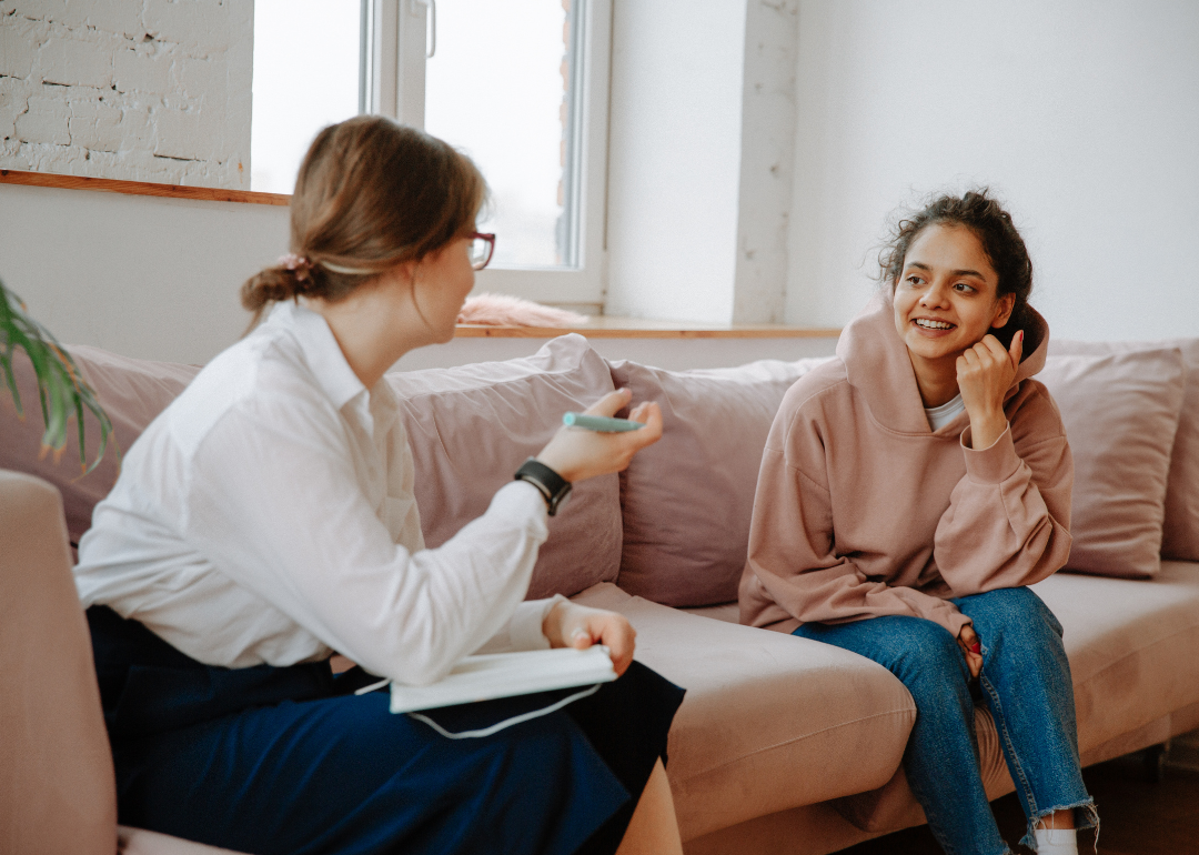 A young woman on a couch talking with a therapist.