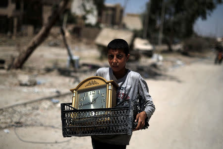 A displaced Iraqi boy carries a clock as he flees from western Mosul, Iraq. REUTERS/Alkis Konstantinidis