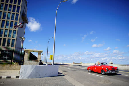 Tourists ride in a vintage car beside the U.S. Embassy in Havana, Cuba, December 12, 2017. REUTERS/Alexandre Meneghini