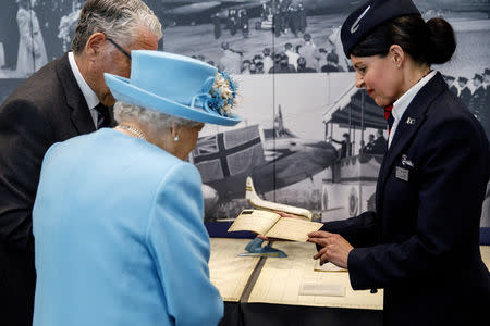 Britain's Queen Elizabeth looks at a 1953 passenger ticket issued in her name displayed at the Heritage Centre during her visit to the headquarters of British Airways, as British Airways mark their centenary year, in Heathrow, west London, Britain May 23, 2019. Tolga Akmen/Pool via REUTERS