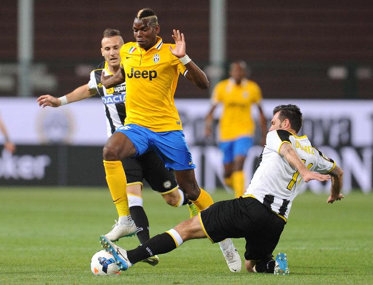 Juventus's Paul Pogba (C) jumps over Udinese's Maurizio Domizzi (R) during the Italian Serie A match at the Friuli Stadium in Udine on April 14, 2014