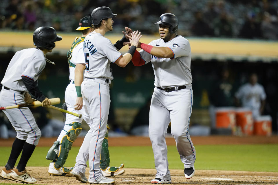 Miami Marlins' Brian Anderson, center, celebrates with Jesús Aguilar, right, after they scored against the Oakland Athletics on Jerar Encarnacion's double during the sixth inning of a baseball game in Oakland, Calif., Tuesday, Aug. 23, 2022. (AP Photo/Godofredo A. Vásquez)