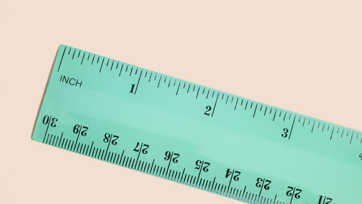 Directly above view of green ruler on a peach-colored background.