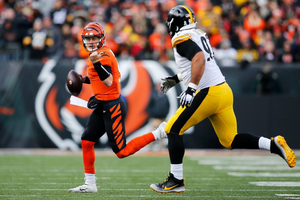 Cincinnati Bengals quarterback Joe Burrow (9) evades Pittsburgh Steelers defensive end Cameron Heyward (97) in the third quarter of the NFL Week 12 game between the Cincinnati Bengals and the Pittsburgh Steelers at Paul Brown Stadium in downtown Cincinnati on Sunday, Nov. 28, 2021. The Bengals beat the Steelers 41-10. 