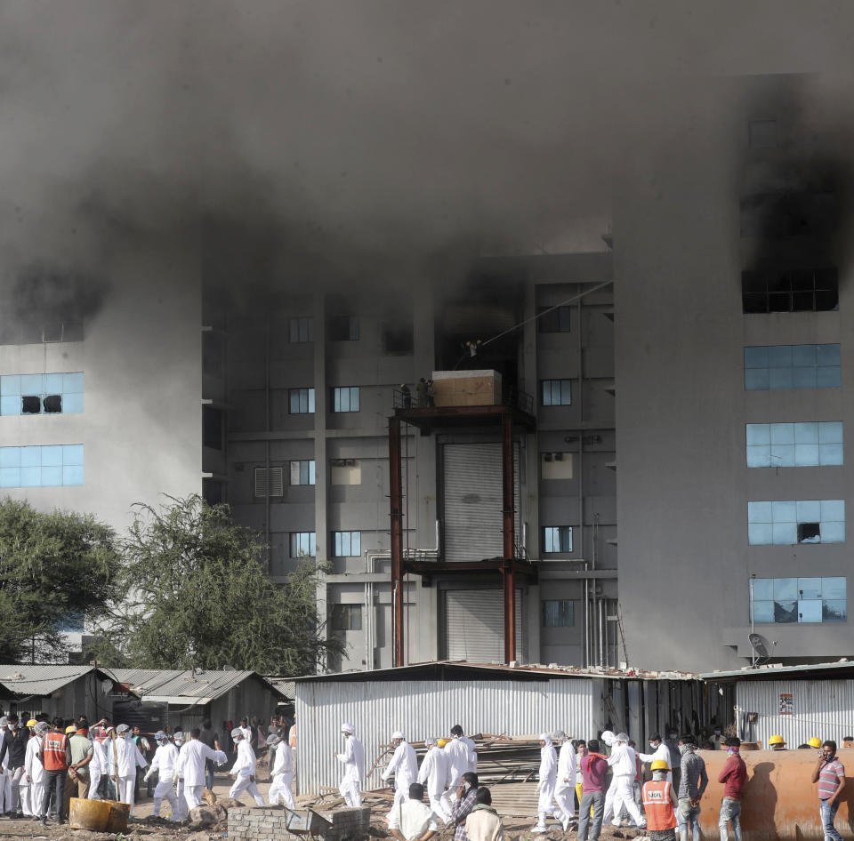 Employees leave as smoke rises from a fire at Serum Institute of India, the world's largest vaccine maker that is manufacturing the AstraZeneca/Oxford University vaccine for the coronavirus, in Pune, India, Thursday, Jan. 21, 2021. (AP Photo/Rafiq Maqbool)