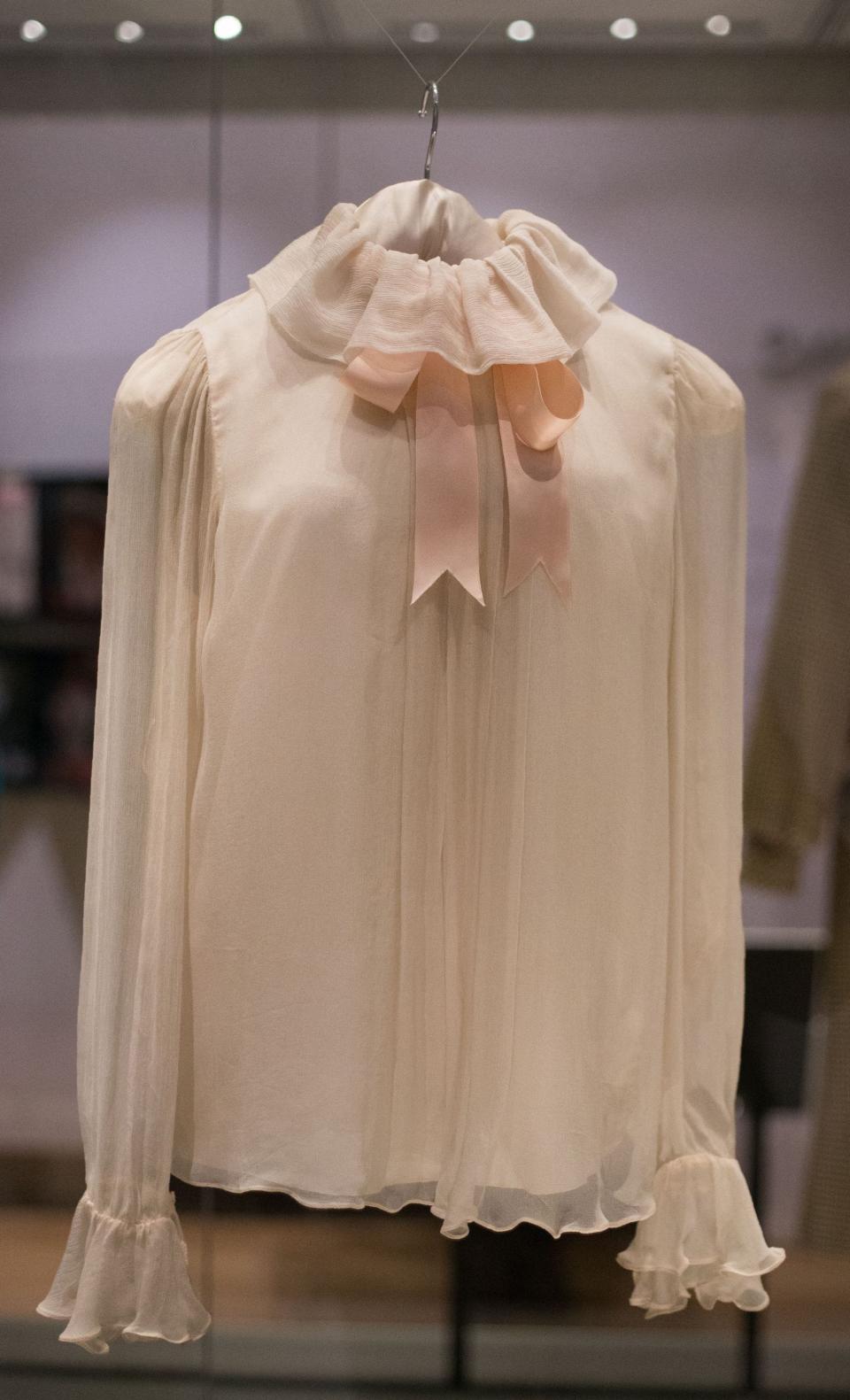 A pink blouse with a ruffled top and a bow on the collar.