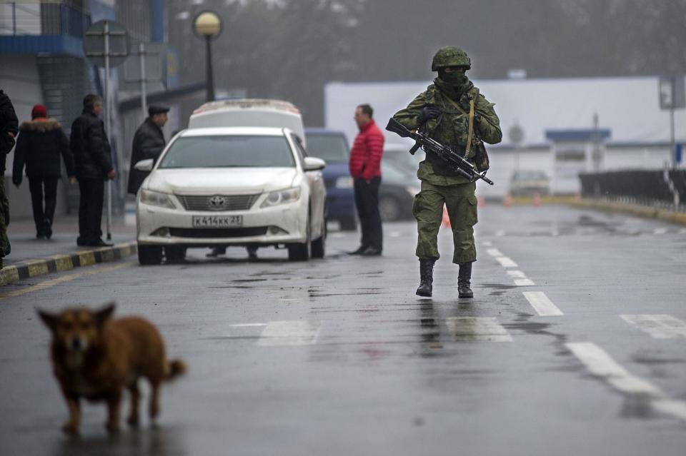 An unidentified armed man patrols a square in front of the airport in Simferopol, Ukraine, Friday, Feb. 28, 2014. Russian military were blocking the airport in the Black Sea port of Sevastopol in Crimea near the Russian naval base while unidentified men were patrolling another airport serving the regional capital, Ukraine's new Interior Minister Arsen Avakov said on Friday. (AP Photo/Andrew Lubimov)