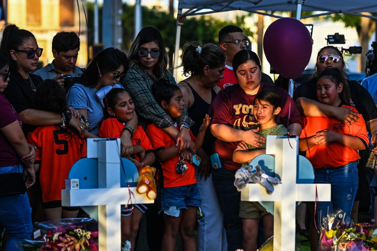 Gabriella Uriegas, second from right, a soccer teammate of Tess Mat,a who died in the shooting, cries while her mother, Geneva Uriegas, holds her as they visit a makeshift memorial outside the Uvalde County Courthouse in Texas.