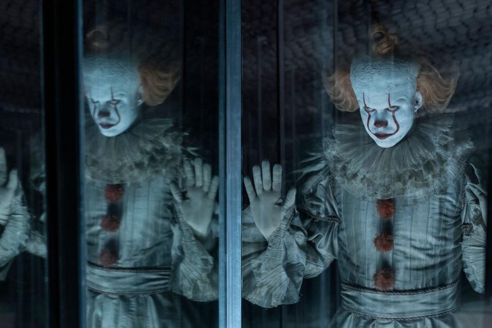 Bill Skarsgard as Pennywise looking through a funhouse mirror