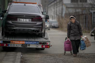 A woman carrying shopping bags walks by a luxury vehicle which was seized in a case against media influencer Andrew Tate, is towed away, on the outskirts of Bucharest, Romania, Saturday, Jan. 14, 2023. Prosecutors seized several luxury vehicles after Tate lost a second appeal this week at a Bucharest court, where he challenged the seizure of assets in the late December raids, including properties, land, and a fleet of luxury cars. More than 10 properties and land owned by companies registered to the Tate brothers have also been seized so far. (AP Photo/Andreea Alexandru)