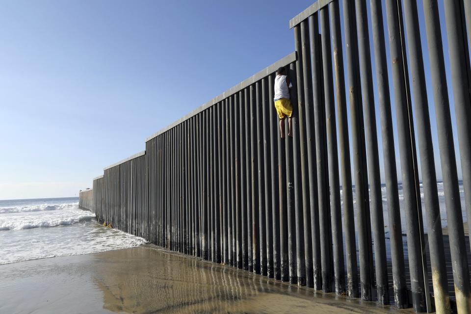 Central American migrant Cristian Andino, 16, from Honduras, gets down from the border structure installed in the Pacific Ocean in Tijuana, Mexico, Friday, Nov. 16, 2018. With about 3,000 Central American migrants having reached the Mexican border across from California and thousands more anticipated, the mayor of Tijuana said Friday that the city was preparing for an influx that will last at least six months and may have no end in sight. (AP Photo/Rodrigo Abd)