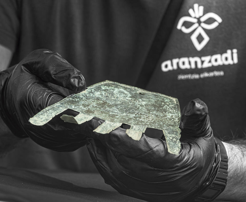 In this undated photo provided by Sociedad de Ciencias Aranzadi, a flat piece of bronze shaped like a human hand is held in the Navarra region. Investigators in northern Spain believe they have discovered the oldest written record of a precursor of the Basque language, pushing back its earliest evidence to the first century B.C. The Aranzadi Science Society revealed the inscription found on a flat piece of bronze shaped like a human hand that archaeologists unearthed last year. Investigators believe it is the earliest known evidence of a written Vasconic language, the precursor of modern Basque, a minority language still spoken in parts of northern Spain and southwest France. It challenges the wide-held belief the Vascones started writing in their language after the introduction of the Latin script by Roman invaders.(Juantxo Egana/Sociedad de Ciencias Aranzadi via AP)
