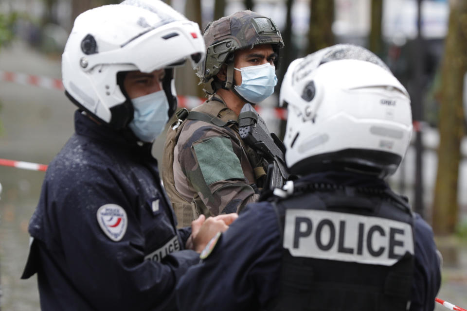 An armed French soldier (backC) stands guards past policemen as he secures the area after several people were injured near the former offices of the French satirical magazine Charlie Hebdo following an attack by a man wielding a knife in the capital Paris on September 25, 2020. - Four people were injured, two seriously, in a knife attack in Paris on September 25, 2020, near the former offices of French satirical magazine Charlie Hebdo, a source close to the investigation told AFP. Two of the victims were in a critical condition, the Paris police department said, adding two suspects were on the run. The stabbing came as a trial was underway in the capital for alleged accomplices of the authors of the January 2015 attack on the Charlie Hebdo weekly that claimed 12 lives. (Photo by GEOFFROY VAN DER HASSELT / AFP) (Photo by GEOFFROY VAN DER HASSELT/AFP via Getty Images)