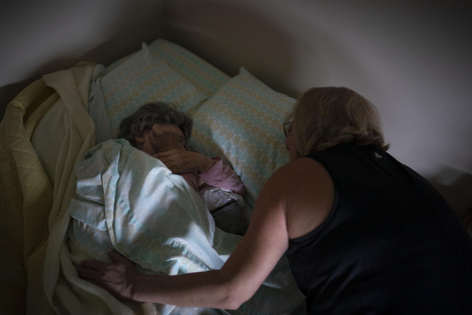 Susan Ryder wakes her mother, Betty Bednarowski, Tuesday, Nov. 30, 2021, in Rotterdam Junction, N.Y. Bednarowski struggles to remember who her family members are. But from the moment she wakes to Ryder’s touch, she is reminded that this is home. (AP Photo/Wong Maye-E)