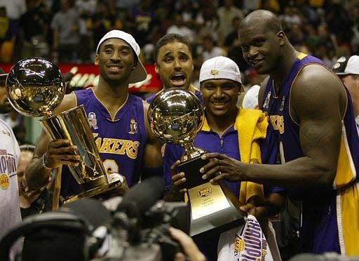 Los Angeles Lakers Kobe Bryant, left, holding the championship trophy, celebrates with teammates Rick Fox, Lindsey Hunter, second from right, and Shaquille O&#x2019;Neal, right, holding the MVP trophy, after winning Game 4 of the NBA Finals, Wednesday, June 12, 2002, in East Rutherford, N.J. The Lakers defeated the New Jersey Nets 113-107, capturing their third consecutive NBA championship.