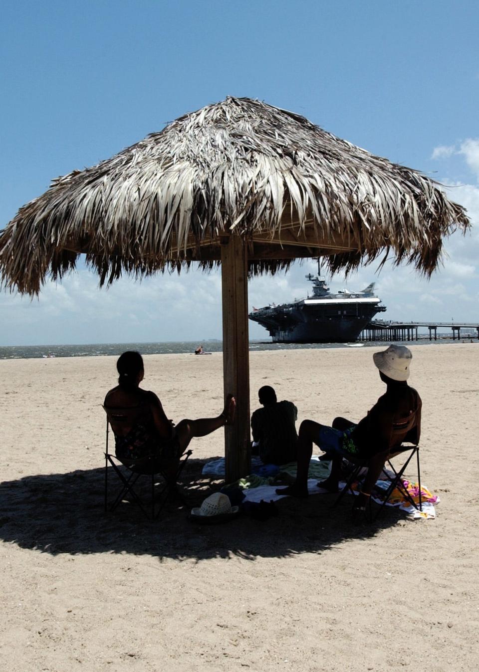 Tourists take it easy at North Beach in Corpus Christi. The U.S.S. Lexington looms in the background.