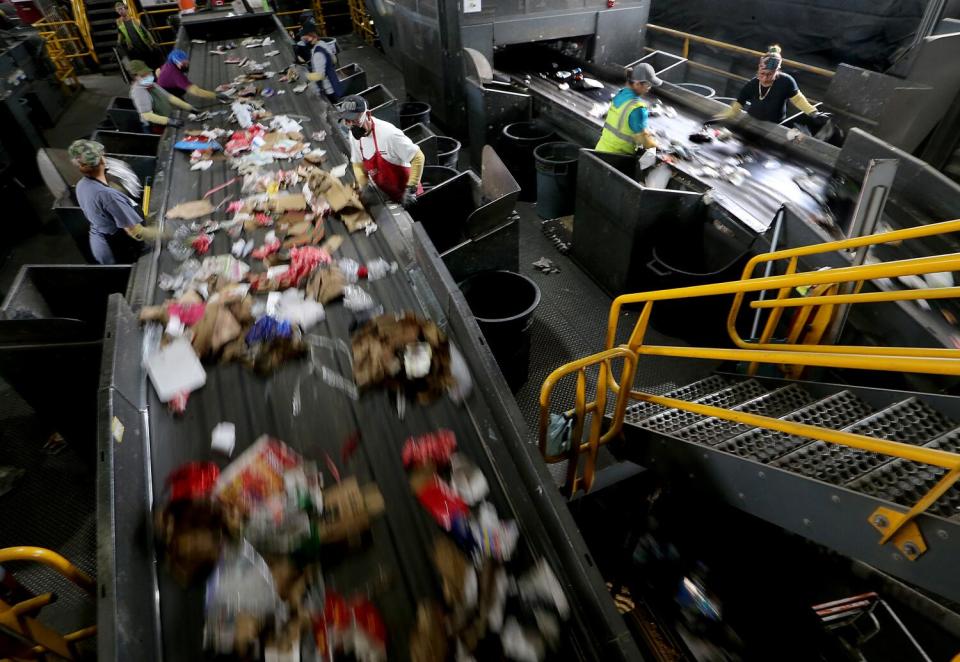 Workers sort through waste traveling on a conveyor belt inside the Athens material recovery facility in Sun Valley.