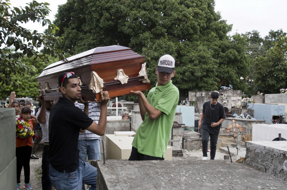 In this Oct. 31, 2018 photo, relatives hoist the coffin that contains the remains of Wilmer Gerardo Nunez onto a burial site at a cemetery in San Pedro Sula, Honduras. Nunez was not the oldest of the 10 children in the family, but he was the one who looked out for the others. He sent money home from the U.S. and called his mother almost every day. (AP Photo/Moises Castillo)