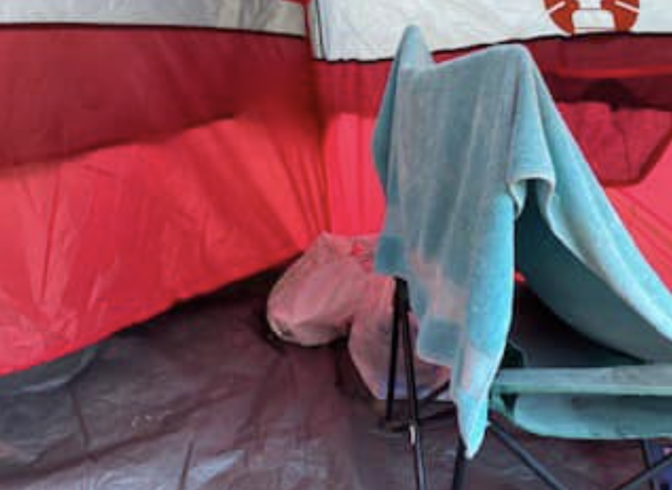 A towel and a chair are seen inside the tent. 