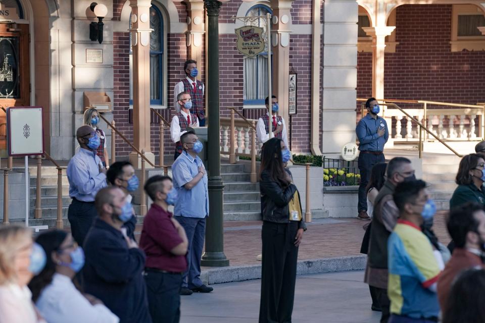 Disneyland cast Members watch as Color Guard members raise the flag inside of Disneyland.