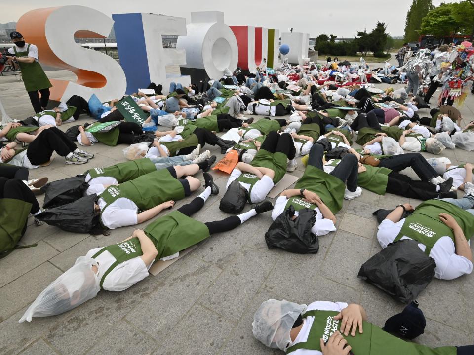 South Korean environmental activists lie on the ground with plastic waste during a campaign marking Earth Day at a park along the Han River in Seoul (AFP via Getty Images)