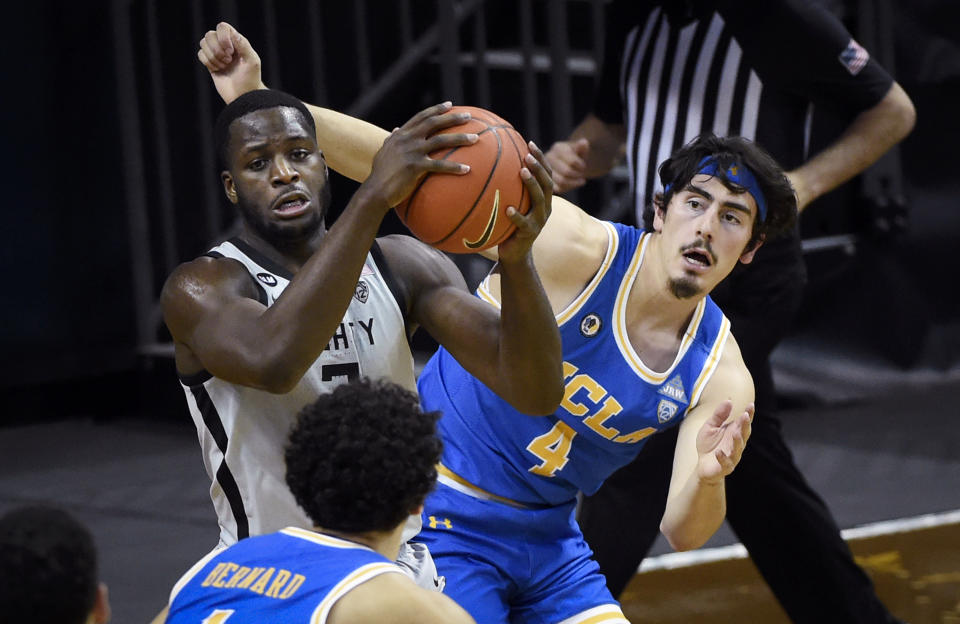 Oregon forward Eugene Omoruyi (2) hauls in a rebound next to UCLA guard Jaime Jaquez Jr. (4) during the first half of an NCAA college basketball game Wednesday, March 3, 2021, in Eugene, Ore. (AP Photo/Andy Nelson)