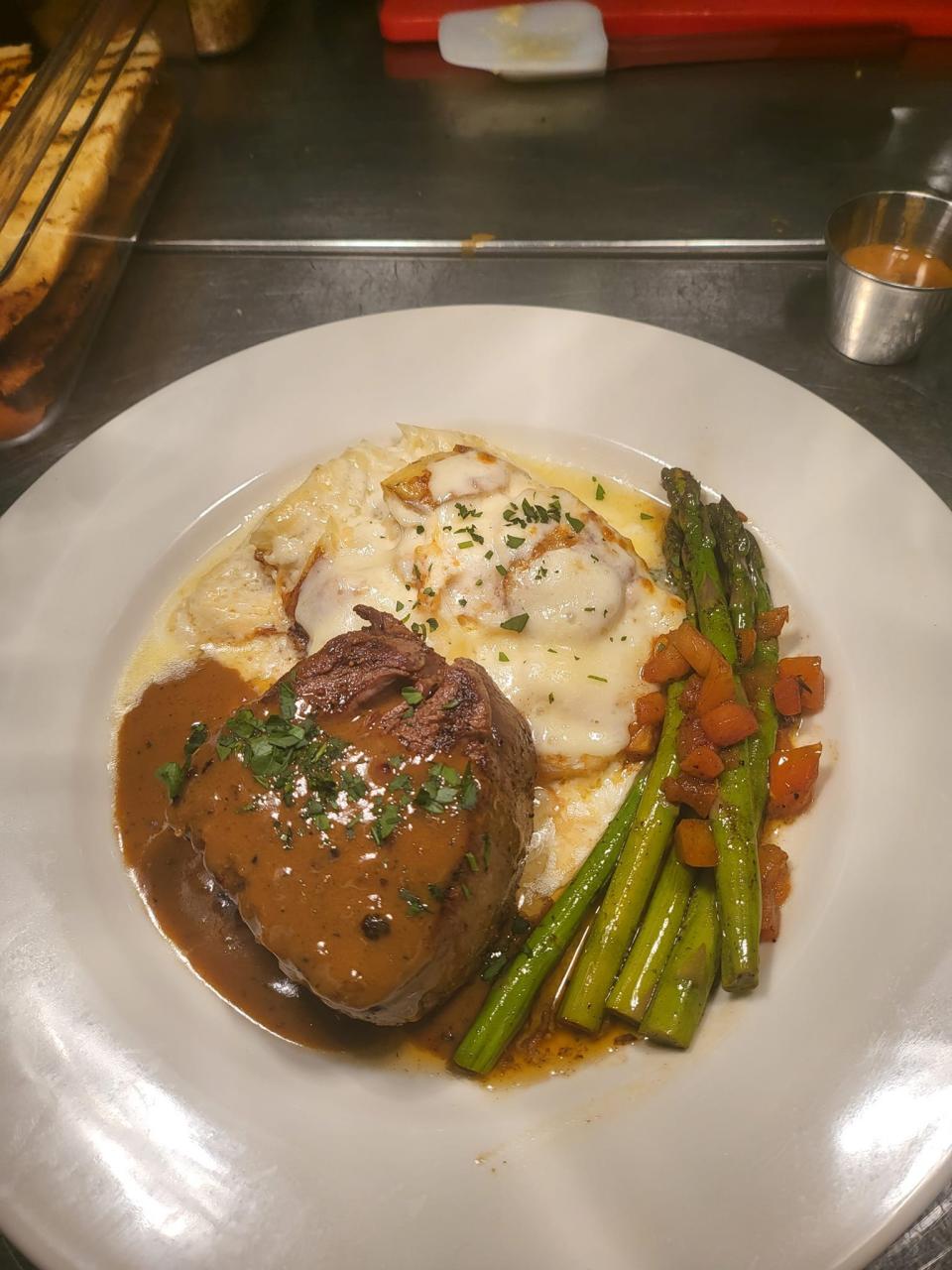 Bistro 55's pavé de boeuf is served with potatoes au gratin and steamed asparagus in a black pepper cognac sauce.