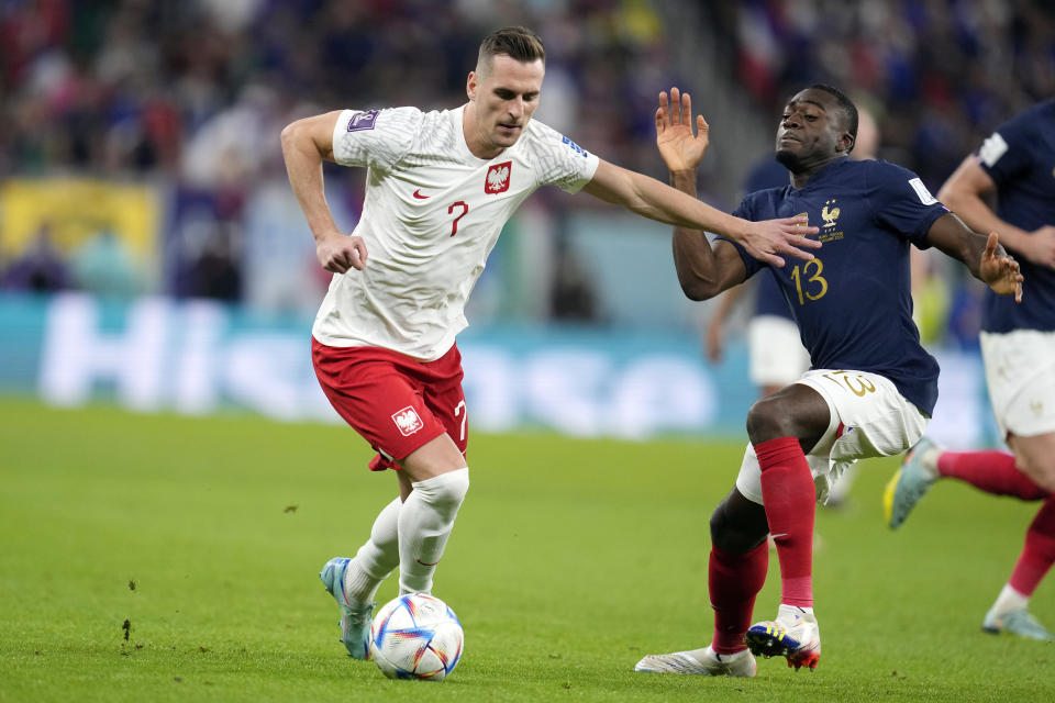 Poland's Arkadiusz Milik, left, and France's Youssouf Fofana, right, fight for the ball during the World Cup round of 16 soccer match between France and Poland, at the Al Thumama Stadium in Doha, Qatar, Sunday, Dec. 4, 2022. (AP Photo/Natacha Pisarenko)