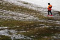 FILE - A young boy crosses a meadow with snow at a slope in Filzmoos south of Salzburg, Austria, Thursday, Jan. 5, 2023. Sparse snowfall and unseasonably warm weather in much of Europe is allowing green grass to blanket many mountaintops across the region where snow might normally be. (AP Photo/Matthias Schrader, File)