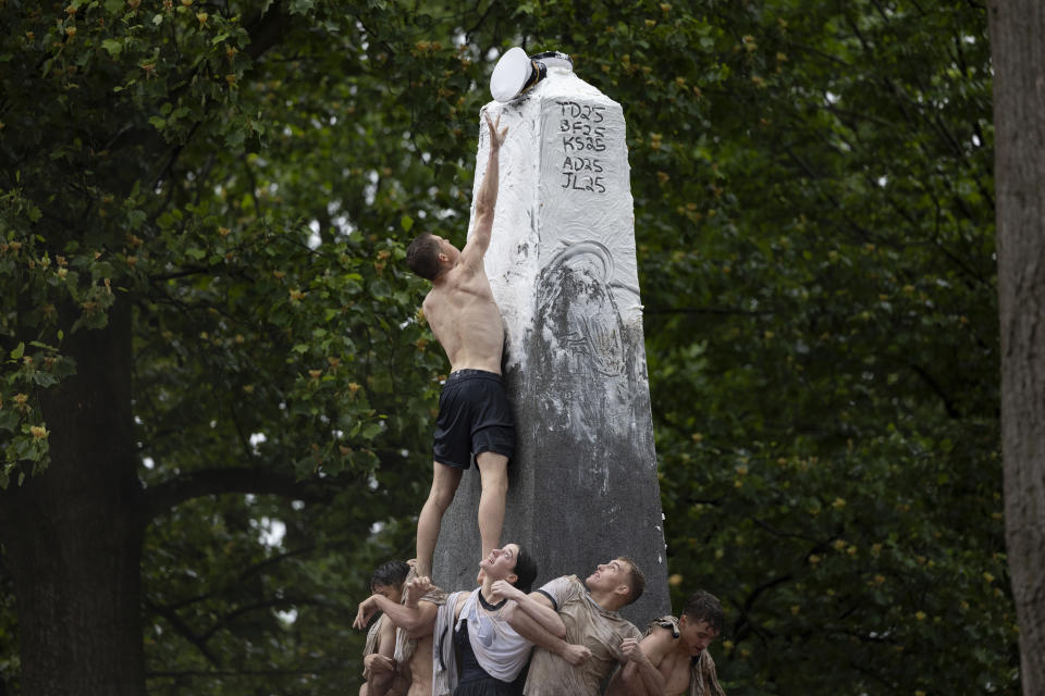 Plebe Ben Leisegang, of California, places an upperclassman's hat atop the Herndon Monument at the U.S. Naval Academy, Wednesday, May 15, 2024, in Annapolis, Md. Freshmen, known as Plebes, participate in the climb to celebrate finishing their first year at the academy. The climb was completed in two hours, nineteen minutes and eleven seconds. (AP Photo/Tom Brenner)