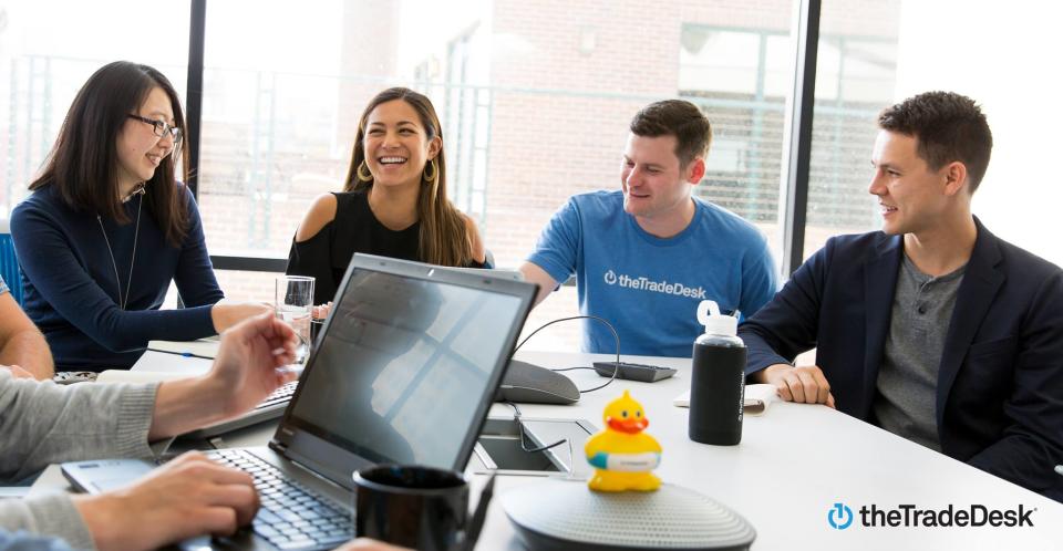 A group of people sitting around a conference room table, one with a laptop.