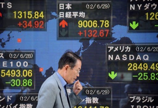 A man walks past an stock prices screen in the window of a securities company in Tokyo. Asian markets mostly fell after US Federal Reserve chief Ben Bernanke warned of a further slowdown in the US economy and a "frustratingly slow" rise in employment