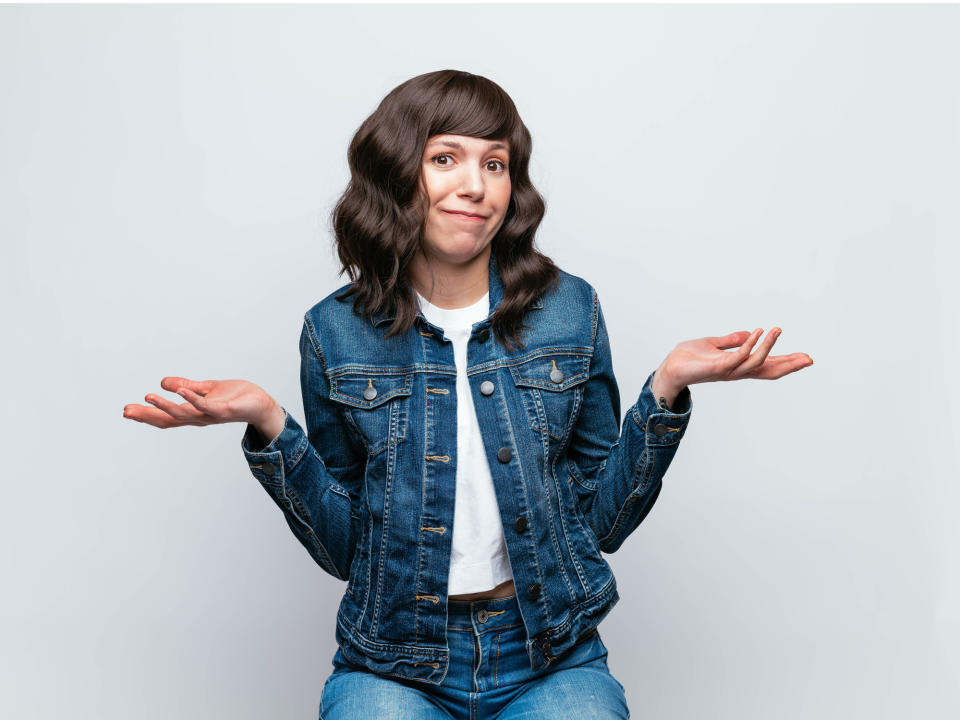 a woman wearing denim and shrugging