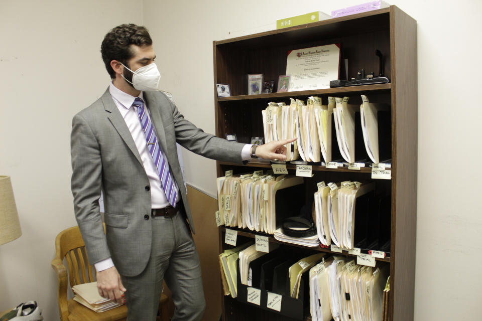 Public defender Drew Flood with the nonprofit law firm Metropolitan Public Defender looks his files for the criminal cases he is currently working on in this May 5, 2022, photo in Portland, Ore. Flood, who was hired eight months ago by the firm, is carrying 100 cases and says he sometimes has so many cases he can't remember details such as what is in the client's police report or what plea deal is being offered. A post-pandemic glut of delayed cases has exposed shocking constitutional landmines impacting defendants and crime victims alike in Oregon, where an acute shortage of public defenders has even led judges to dismiss serious cases. (AP Photo/Gillian Flaccus)