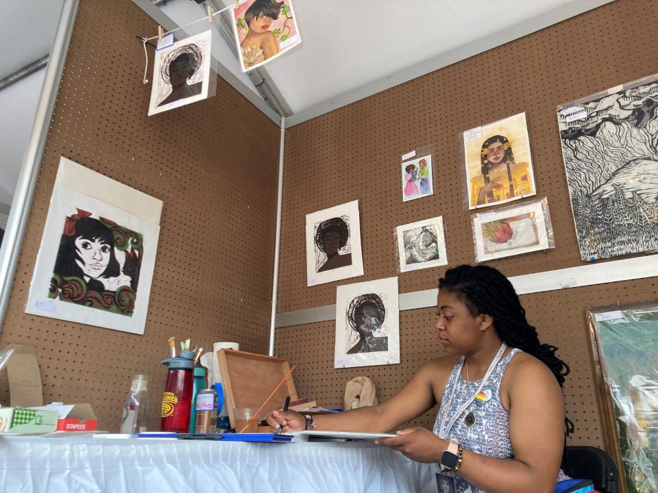 Jamila Johnson, 23, signs a print she sold at her Des Moines Arts Festival booth in 2021. The Ames artist is a part of the Emerging Iowa Artist Program presented by Principal, which showcases young visual artists from Iowa.